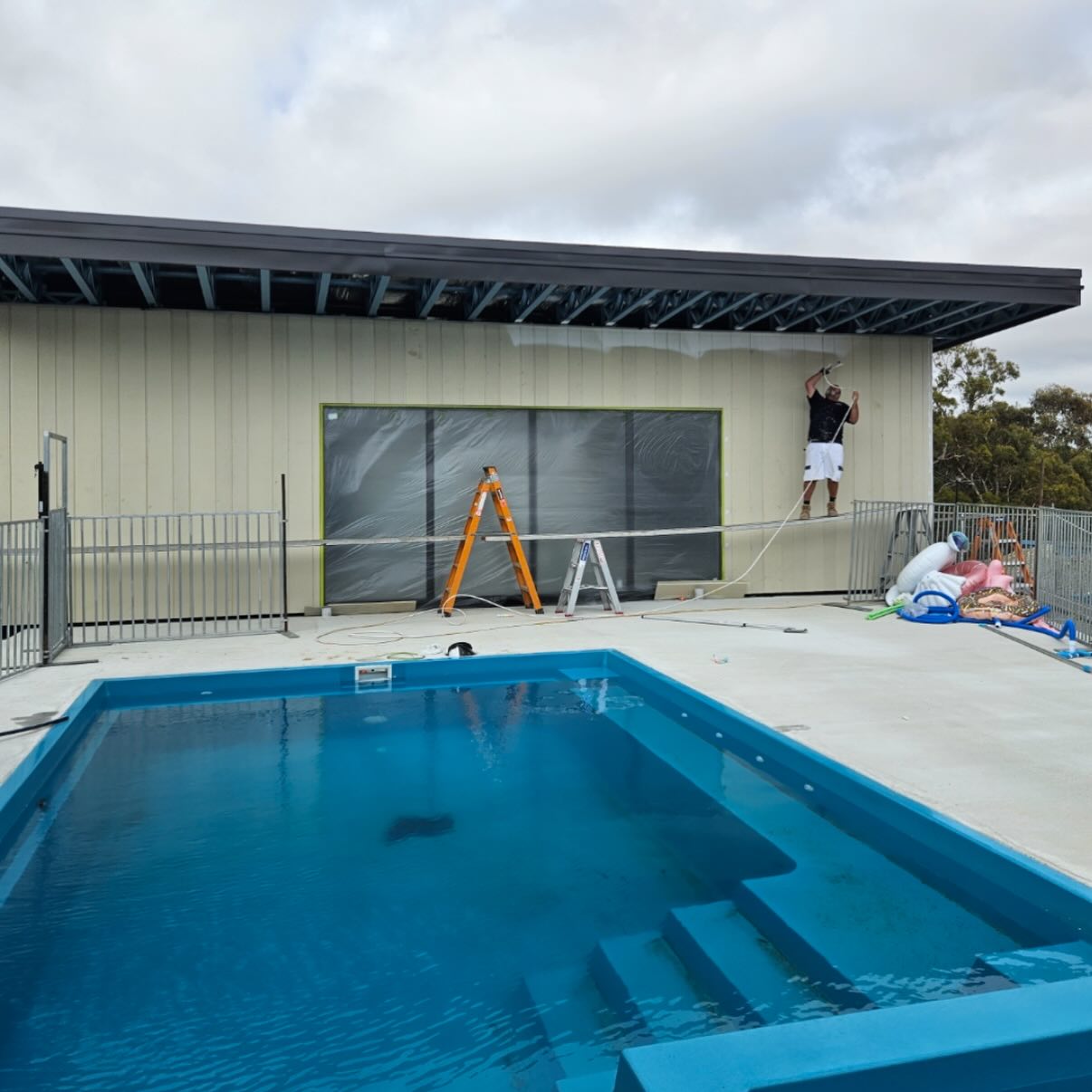Exterior painting underway beside a pool area